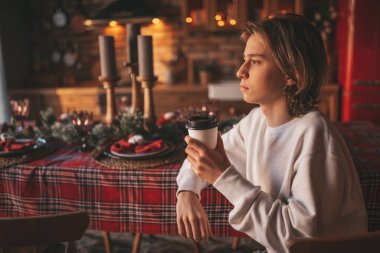 Uzun saçlı, düşünceli üzgün bakışlı, sinirli ve evde ağlayan genç bir çocuk. Şık bir zoomer olan Z jenerasyonu, yeni yıl tatilinde Noel ağacı ışıklarıyla süslenmiş 25 Aralık arifesi.