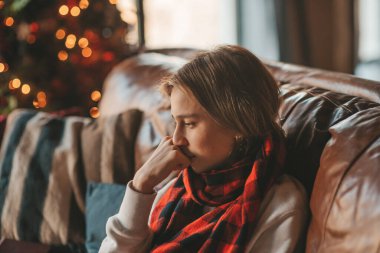 Uzun saçlı, düşünceli üzgün bakışlı, sinirli ve evde ağlayan genç bir çocuk. Şık bir zoomer olan Z jenerasyonu, yeni yıl tatilinde Noel ağacı ışıklarıyla süslenmiş 25 Aralık arifesi.