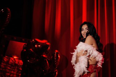 Young tempting brunette asian woman with perfect skin posing in red room.