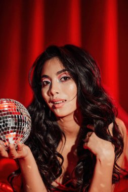 Curly black hair asian model with disco ball posing in bed on Valentine's day