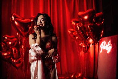 Beautiful asian black hair woman in sexy lingerie posing with cupcake in a room decorated for Valentine's Day
