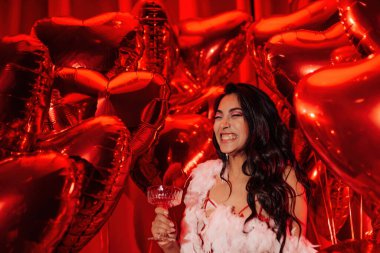 Young tempting brunette woman in sexy lace underwear and feather boa having fun with champagne on Valentine's day