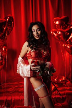 Brunette japanese woman wearing sexy lace underwear posing on red glamour background 