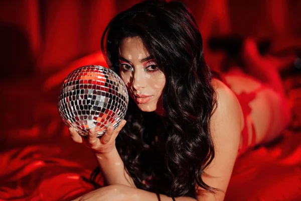 Curly black hair asian model with disco ball posing in bed on Valentine\'s day