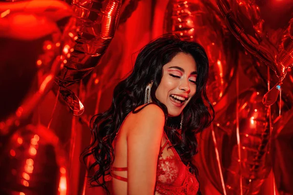 Young japanese brunette woman in lace underwear posing on red glamour background