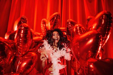 Young tempting brunette woman in sexy lace underwear and feather boa having fun with champagne on Valentine's day