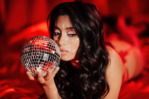 Curly black hair asian model with disco ball posing in bed on Valentine's day