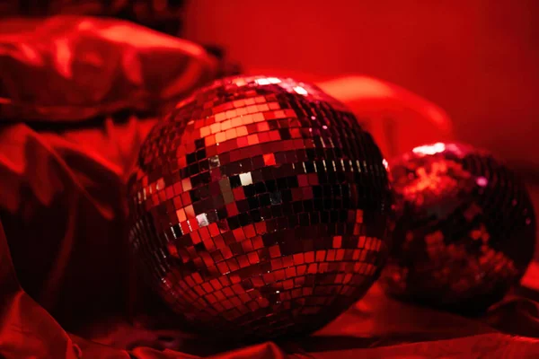 Glossy mirror balls in extravagant atmosphere interior decoration at vivid red glamour background. Beautiful place for saint valentines holiday with disco balls in romantic burlesque bedroom.