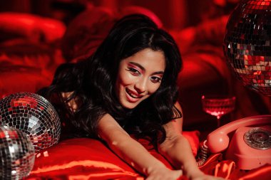 Sexy asian sensual model in red lace underwear posing with disco balls in bed on Valentine's day 
