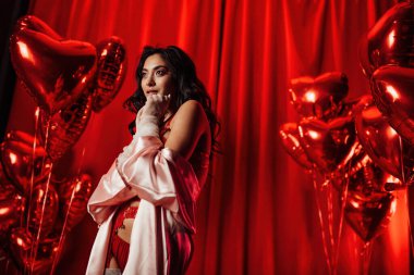 Sensual young japanese woman wearing sexy lace underwear posing on red glamour background 