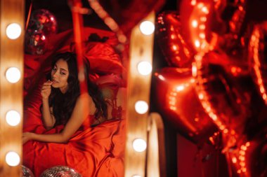 Reflection in the mirror of a asian model in lace underwear lying on bed with red silk sheet