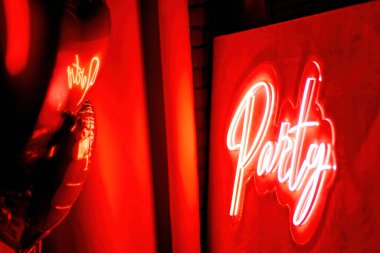 Extravagant bedroom luxury interior with love glamour decoration at Valentines day in studio. Party lettering and balloons by heart shaped and at illuminated mirror romantic cozy atmosphere at red background.