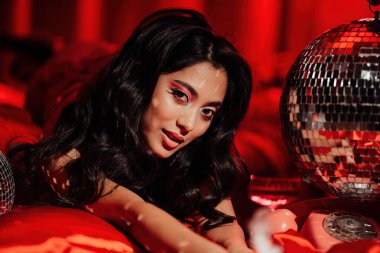 Curly black hair asian model with disco ball posing in bed on Valentine's day