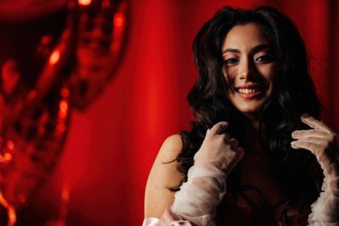 Close up portrait of attractive asian woman with perfect skin posing in a red room, copy space 