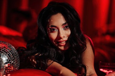 Curly black hair asian model with disco ball posing in bed on Valentine's day