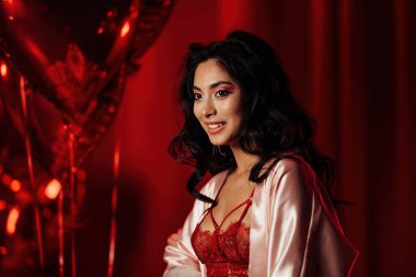 Brunette woman in sexy underwear posing in a room decorated for Valentine's Day