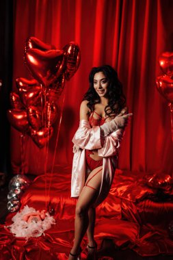 Sensual young japanese woman wearing sexy lace underwear posing in full growth on red glamour background 