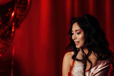 Close up portrait of attractive asian woman with perfect skin posing in a red room, copy space 