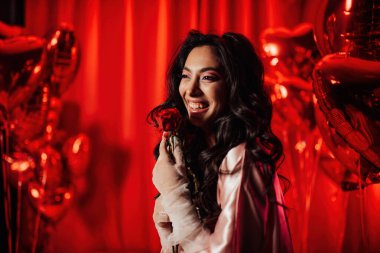 Beautiful young japanese woman in sexy lace underwear and fishnet gloves posing with roses on red glamour background