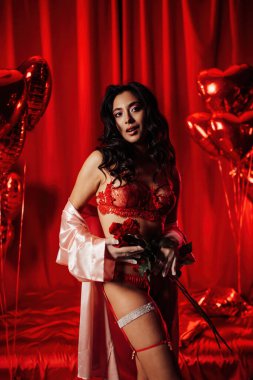 Young japanese woman wearing sexy lace underwear posing with roses on red glamour background 