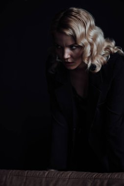 Young adult beauty woman in formal evening suit of black color with lace bra at thoughtful. Stylish blonde curly hair sensual model fashionista posing at studio in fashion pantsuit