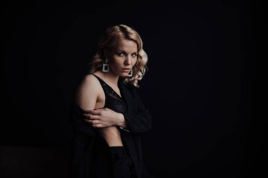 Young adult beauty woman in formal evening suit of black color with lace bra at thoughtful. Stylish blonde curly hair sensual model fashionista posing at studio in fashion pantsuit