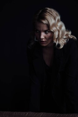 Young adult beauty woman in formal evening suit of black color with lace bra at thoughtful. Stylish blonde curly hair sensual model fashionista posing at studio in fashion pantsuit