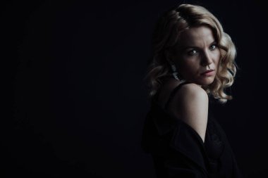 Young adult beauty woman in formal evening suit of black color with lace bra at thoughtful. Stylish blonde curly hair sensual model fashionista posing at studio in fashion pantsuit