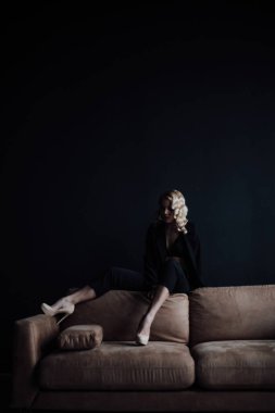 Young adult beauty woman in formal evening suit of black color with lace bra at thoughtful. Stylish blonde curly hair sensual model fashionista posing at studio in fashion pantsuit