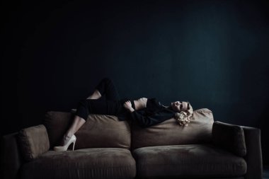 Young adult beauty woman in formal evening suit of black color with lace bra at thoughtful. Stylish blonde curly hair sensual model fashionista posing at studio in fashion pantsuit