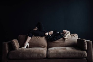 Young adult beauty woman in formal evening suit of black color with lace bra at thoughtful. Stylish blonde curly hair sensual model fashionista posing at studio in fashion pantsuit