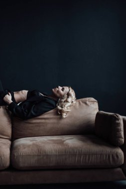 Young adult beauty woman in formal evening suit of black color with lace bra at thoughtful. Stylish blonde curly hair sensual model fashionista posing at studio in fashion pantsuit