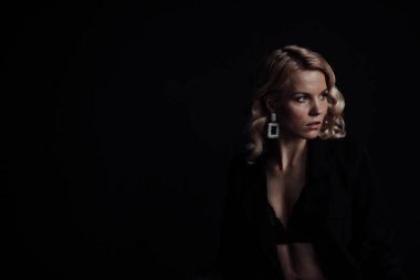 Young adult beauty woman in formal evening suit of black color with lace bra at thoughtful. Stylish blonde curly hair sensual model fashionista posing at studio in fashion pantsuit