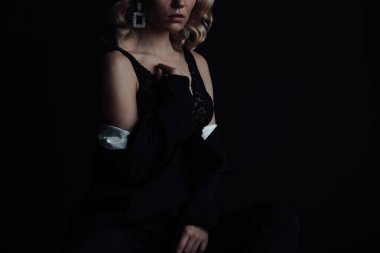 Young adult beauty woman in formal evening suit of black color with lace bra at thoughtful. Stylish blonde curly hair sensual model fashionista posing at studio in fashion pantsuit