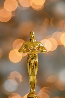 Hollywood altın Oscar ödüllü biblo taklidi bir ödül töreni sırasında görüldü. Başarı ve zafer konsepti parlak sarı ışıklar arka planında heykelciği kapatın