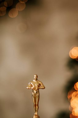 Hollywood gold oscars trophy figurine imitation seen during an award cinema ceremony. Success and victory concept close up statuette at twinkle yellow lights background