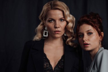 Yetişkin, zarif, çok ırklı genç kızlar resmi gece kıyafetleriyle farklı renklerde sutyenle. Şık sarışın ve kızıl saçlı moda modacıları. Moda kıyafetleriyle stüdyoda poz veriyorlar. Gömlek yok.