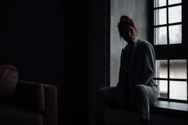 Yetişkin, zarif ve zarif bir kadın resmi akşam gri takımlı, beyaz sütyenli, düşünceli. Havalı, kıvırcık, kıvırcık saçlı, şehvetli model. Moda elbisesiyle stüdyoda poz veren çıplak omuz modamız.