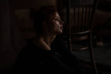 Yetişkin, güzel, zarif bir kadın resmi bir akşam giysisi giymiş, yüzüne siyah bir el değmiş. Havalı, kıvırcık, kıvırcık saçlı, şehvetli model, çıplak omuz modada moda takım elbise ve sutyenle stüdyoda poz veriyor.