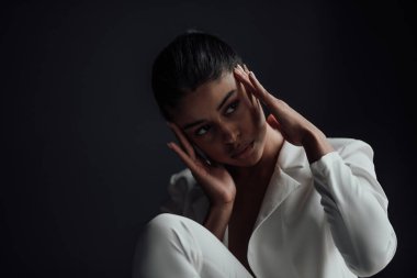 Resmi akşam giysili esmer, genç, güzel bir kadın. Yüzüne tişört değmemiş, beyaz takım elbiseli. Şık, kıvırcık saçlı, şehvetli, Afro-Amerikan manken modayla stüdyoda moda kıyafeti içinde poz veriyor.