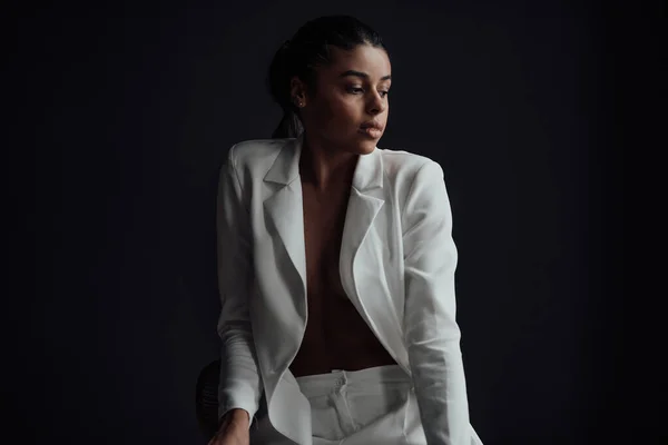 stock image Young adult beauty swarthy woman in formal evening white suit with bra at thoughtful. Stylish black curly hair sensual african american model fashionista posing at studio in fashion pantsuit