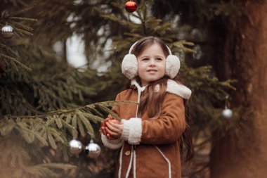 Aktif küçük kız ormanda istirahat edip çocukluk yılbaşı balolarının tadını çıkarıyor. Noel 'i ve yeni yılı kutlayan kadın çocuk kış tatilini dışarıda kutluyor.