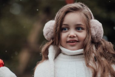 Aktif küçük kız ormanda istirahat edip çocukluk yılbaşı balolarının tadını çıkarıyor. Noel 'i ve yeni yılı kutlayan kadın çocuk kış tatilini dışarıda kutluyor.