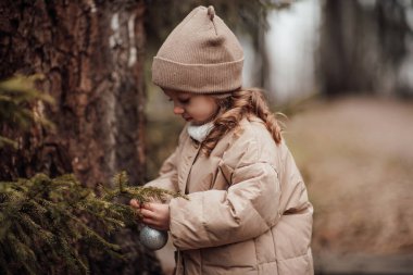 Aktif küçük kız ormanda istirahat edip çocukluk yılbaşı balolarının tadını çıkarıyor. Noel 'i ve yeni yılı kutlayan kadın çocuk kış tatilini dışarıda kutluyor.