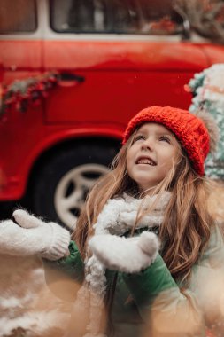 Noel 'i ve yeni yılı kutlayan bayan çocuk kış tatilini dışarıda kutluyor. Aktif küçük kız kozalaklı ormanda çocukluğunun tadını çıkarıyor.