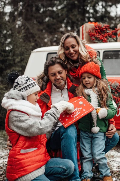 クリスマスと新年の冬の休暇シーズンの屋外を祝う幸せな家族 親と一緒に楽しい時間を過ごすアクティブな子供たちは 最初の雪でXmasバスリージョイスの近くで楽しんで抱擁します — ストック写真