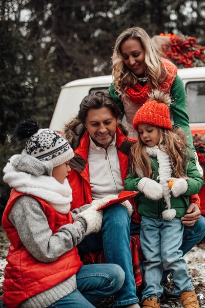 全家在户外欢度圣诞和新年佳节 活跃的孩子们和他们的父母欢欢喜喜地在圣诞大巴旁拥抱快乐 — 图库照片
