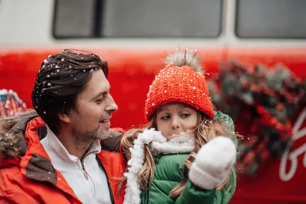 クリスマスと新年の冬の休暇シーズンの屋外を祝う幸せな家族 小さな娘と一緒に楽しい時間を過ごす父親は 最初の雪でXmasバスリージョイスの近くで楽しんで抱擁 — ストック写真