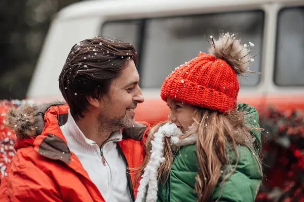 Happy family celebrating Christmas and New Year winter holidays season outdoor. Father with little daughter joyful spending time together hugging having fun near Xmas bus rejoices at first snow