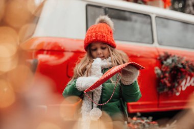 Noel 'i ve yeni yılı kutlayan bayan çocuk kış tatilini dışarıda kutluyor. Küçük kız açık havada Noel Baba 'ya kırmızı zarfla mektup yazıp mucize bekliyor.